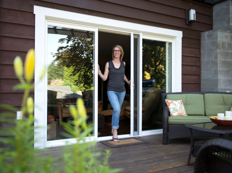 Woman opening ClearView retractable screen on sliding glass patio door